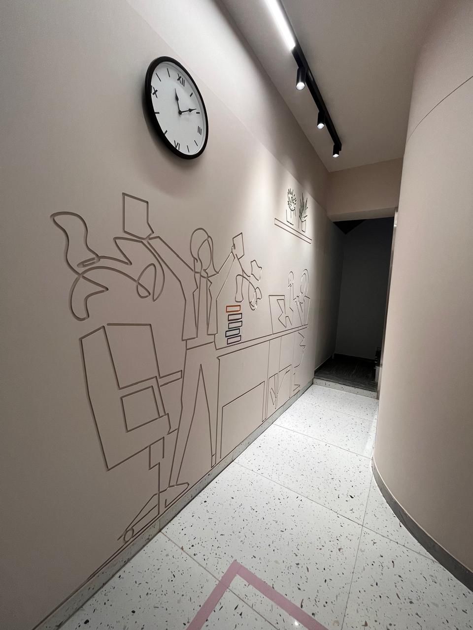 Curved coworking space corridor with an illustrated wall mural and clock